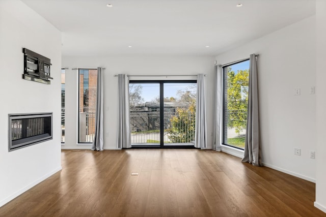 unfurnished living room featuring recessed lighting, wood finished floors, and baseboards