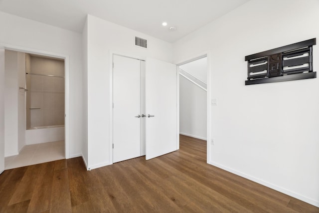 unfurnished bedroom featuring wood finished floors, visible vents, a closet, and baseboards