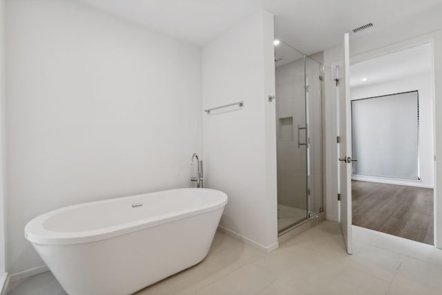 bathroom featuring baseboards, visible vents, a freestanding tub, a stall shower, and tile patterned flooring