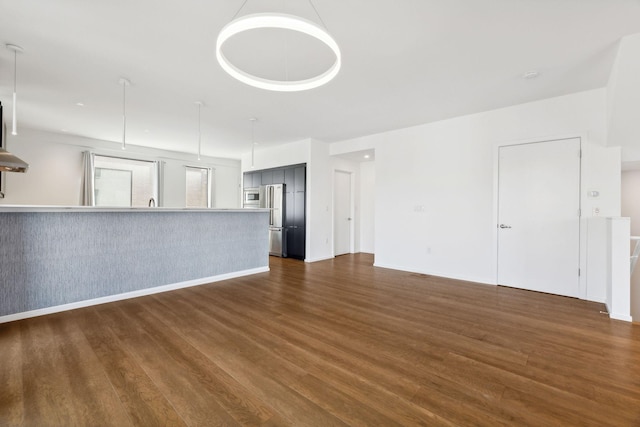 unfurnished living room featuring dark wood-type flooring and baseboards