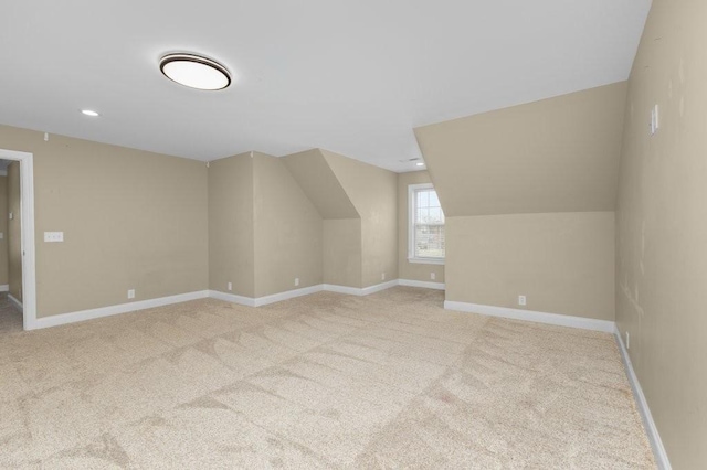 additional living space with baseboards and light carpet