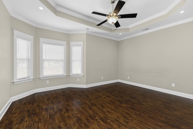 spare room with visible vents, ornamental molding, dark wood finished floors, baseboards, and a raised ceiling