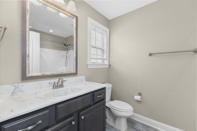 bathroom with baseboards, toilet, walk in shower, and vanity