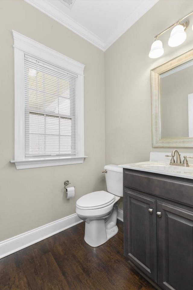 bathroom featuring toilet, crown molding, baseboards, and wood finished floors