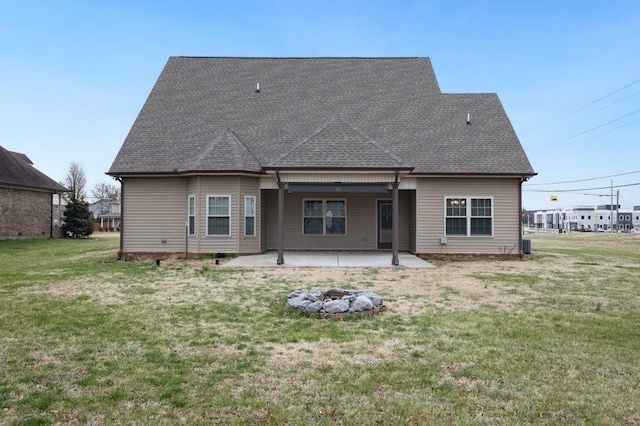 rear view of property featuring a patio area, a shingled roof, and a yard