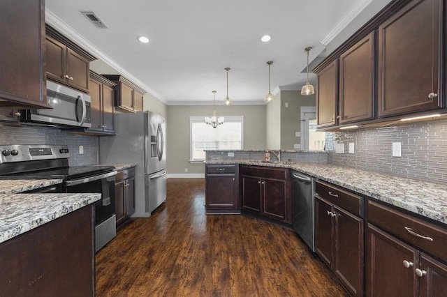 kitchen with a peninsula, ornamental molding, visible vents, and stainless steel appliances