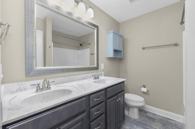 full bathroom with double vanity, toilet, baseboards, and a sink