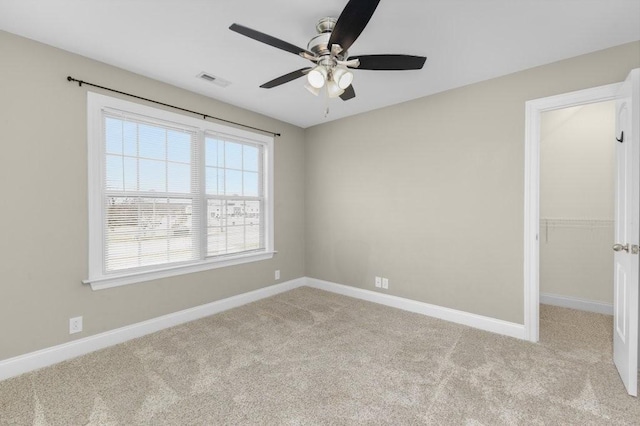 carpeted empty room with a ceiling fan, baseboards, and visible vents