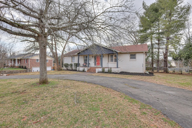 view of front of home featuring a front lawn, fence, brick siding, and driveway