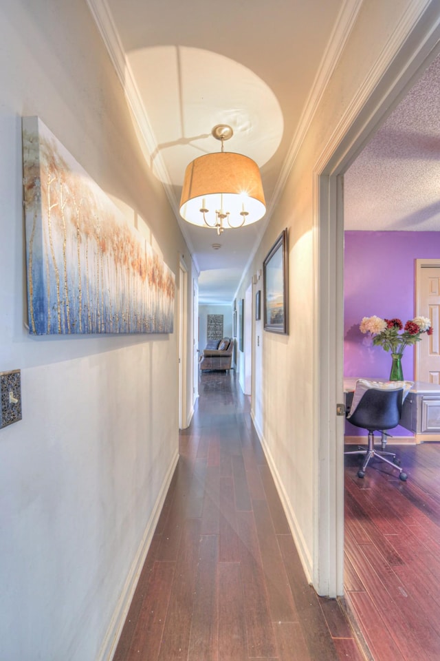 corridor featuring a textured ceiling, crown molding, baseboards, and hardwood / wood-style floors