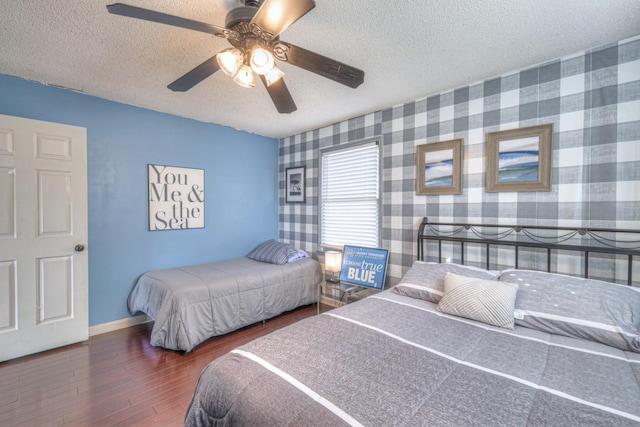 bedroom with wallpapered walls, wood finished floors, baseboards, and a textured ceiling