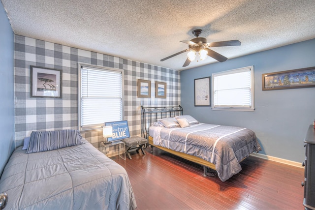 bedroom with wood finished floors, baseboards, wallpapered walls, ceiling fan, and a textured ceiling