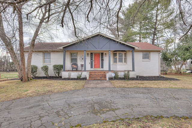 view of front of home featuring brick siding, a porch, and a front yard