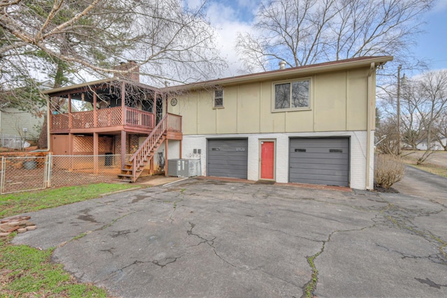 exterior space with stairway, driveway, an attached garage, a chimney, and brick siding