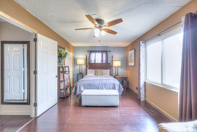 bedroom featuring visible vents, ceiling fan, baseboards, wood finished floors, and a textured ceiling