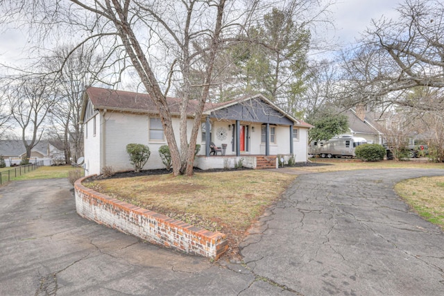 view of front facade with brick siding, covered porch, and a front yard