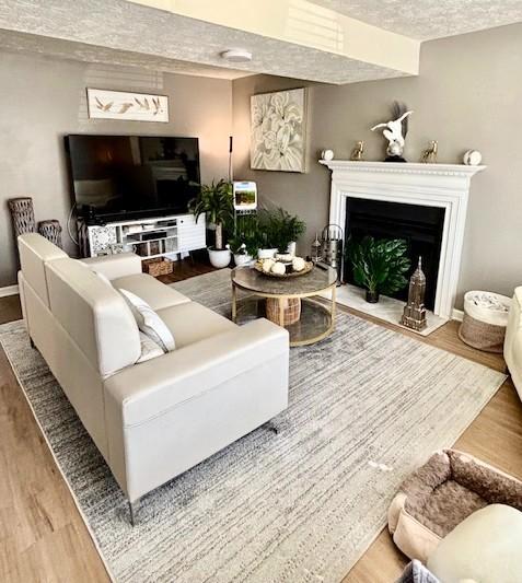 living room featuring baseboards, a fireplace with flush hearth, and wood finished floors