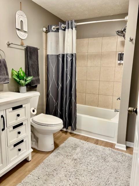 full bath with toilet, shower / tub combo, wood finished floors, a textured ceiling, and vanity