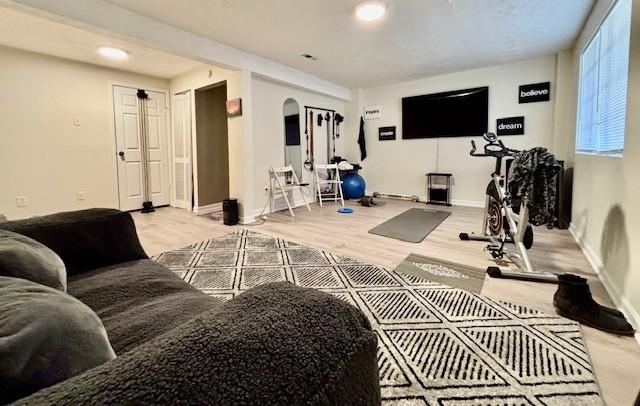 workout room with arched walkways, baseboards, and wood finished floors