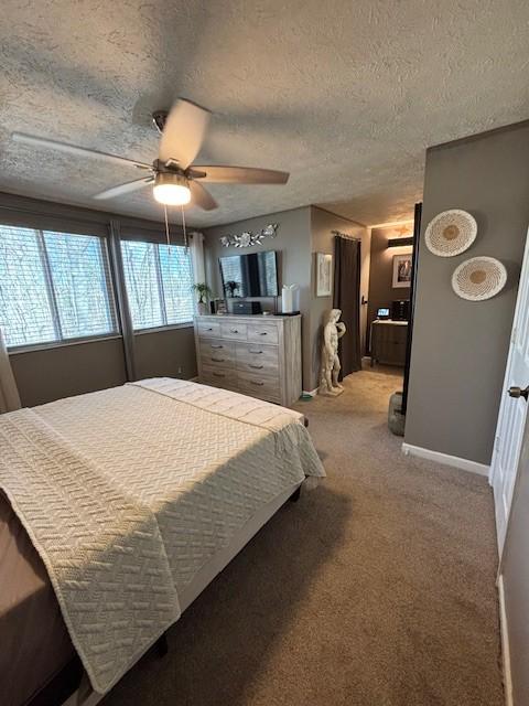 bedroom featuring a ceiling fan, light colored carpet, baseboards, and a textured ceiling