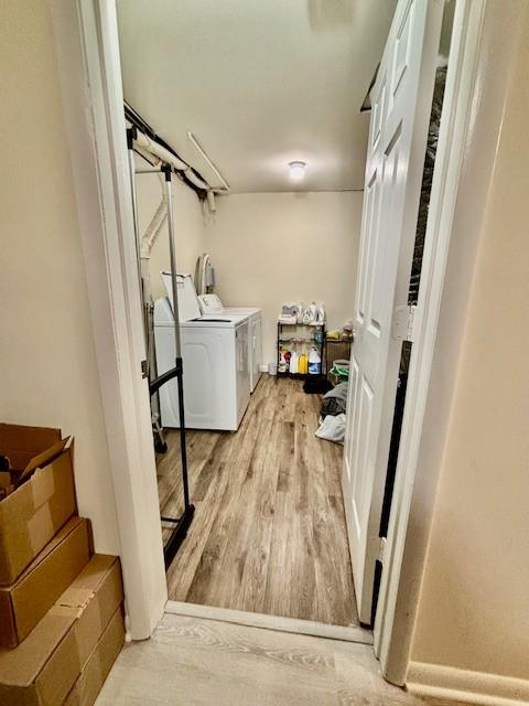 clothes washing area featuring laundry area, light wood-style flooring, and washing machine and clothes dryer