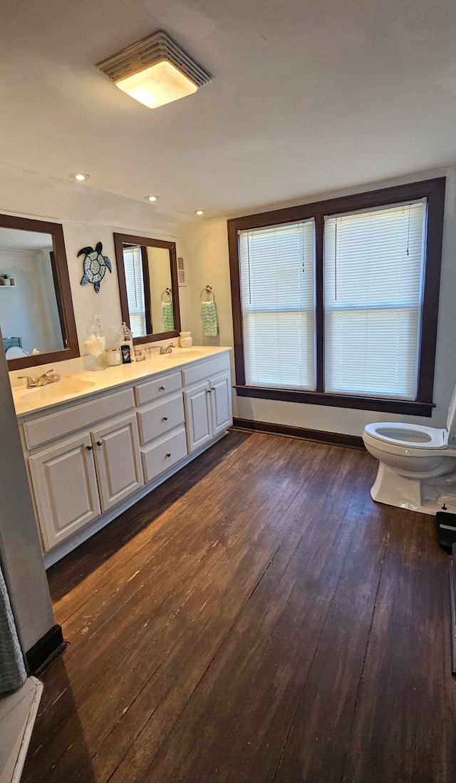 bathroom featuring a sink, toilet, double vanity, recessed lighting, and wood-type flooring