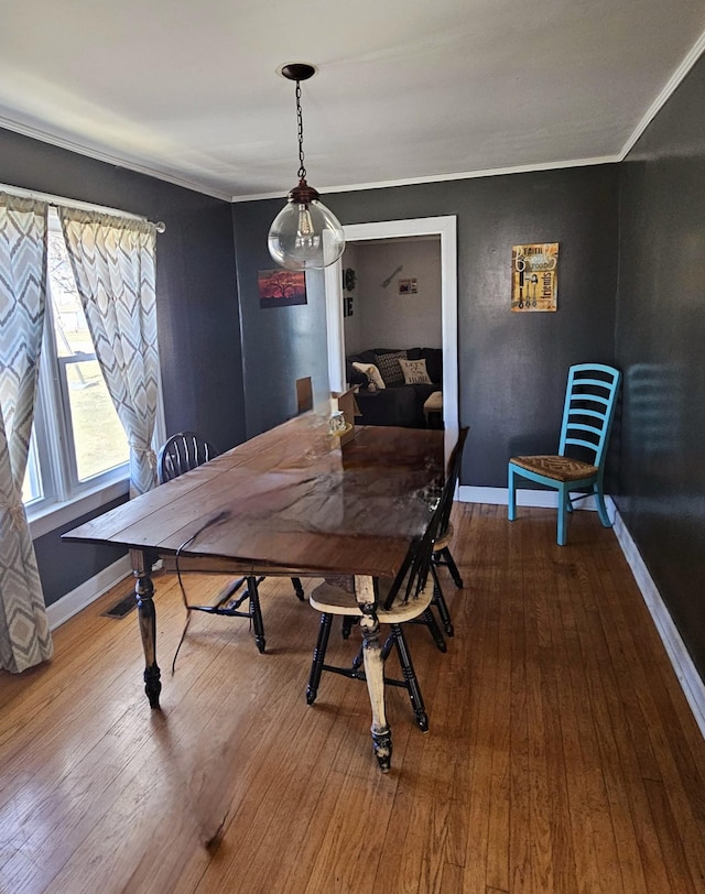 dining area with hardwood / wood-style flooring, baseboards, and ornamental molding