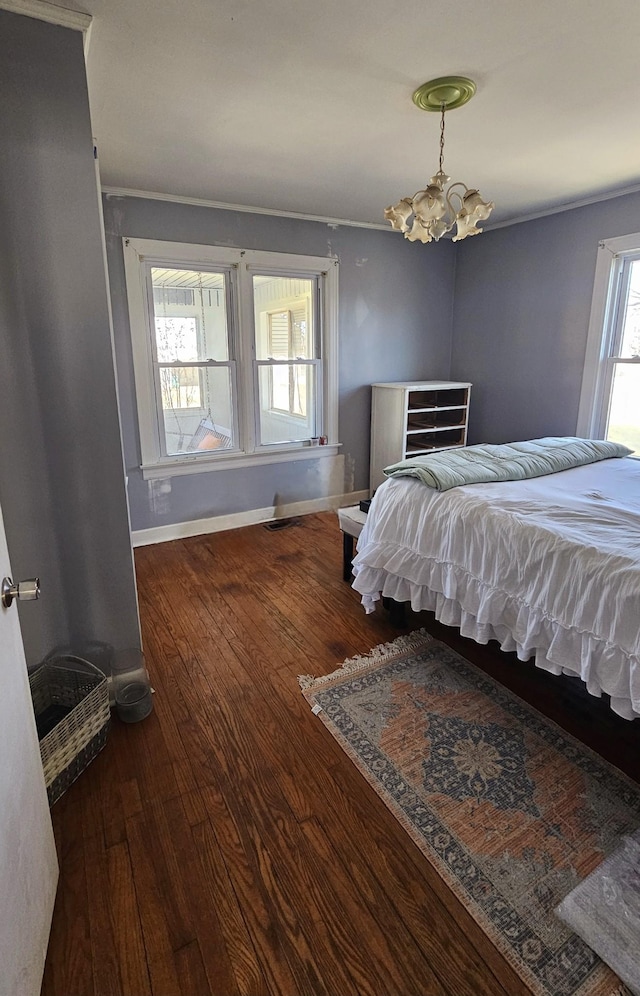 bedroom with hardwood / wood-style flooring, a notable chandelier, baseboards, and ornamental molding