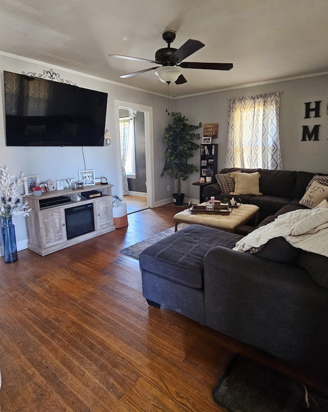 living room featuring dark wood finished floors, crown molding, baseboards, and ceiling fan