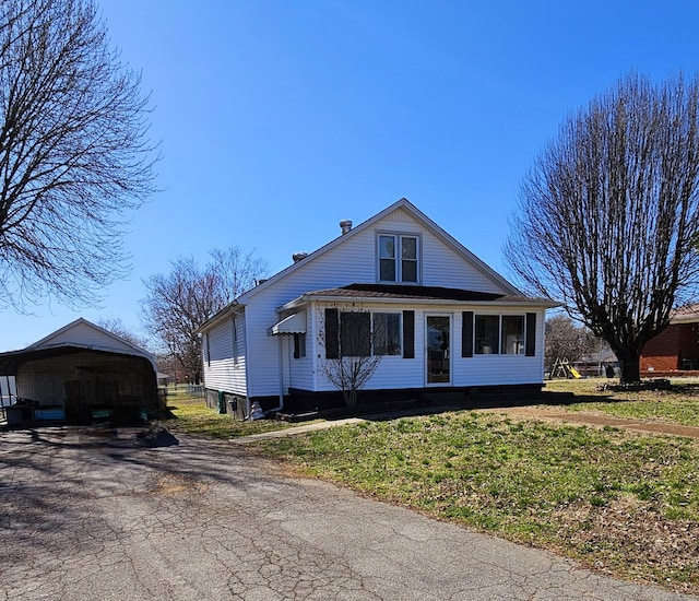 view of front of home with a detached carport, a front yard, and driveway