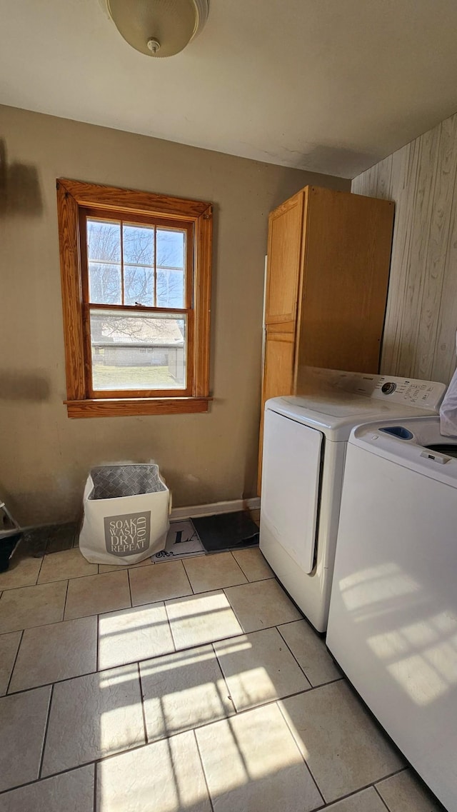 clothes washing area featuring washer and dryer, light tile patterned flooring, and baseboards