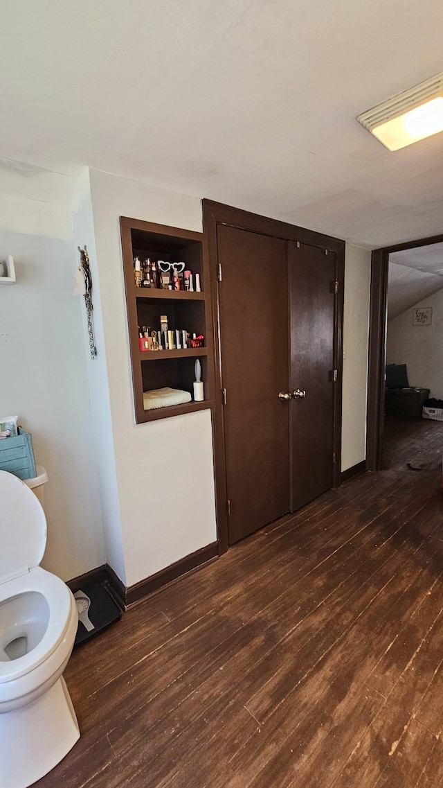 hall with built in shelves, dark wood-style floors, and baseboards