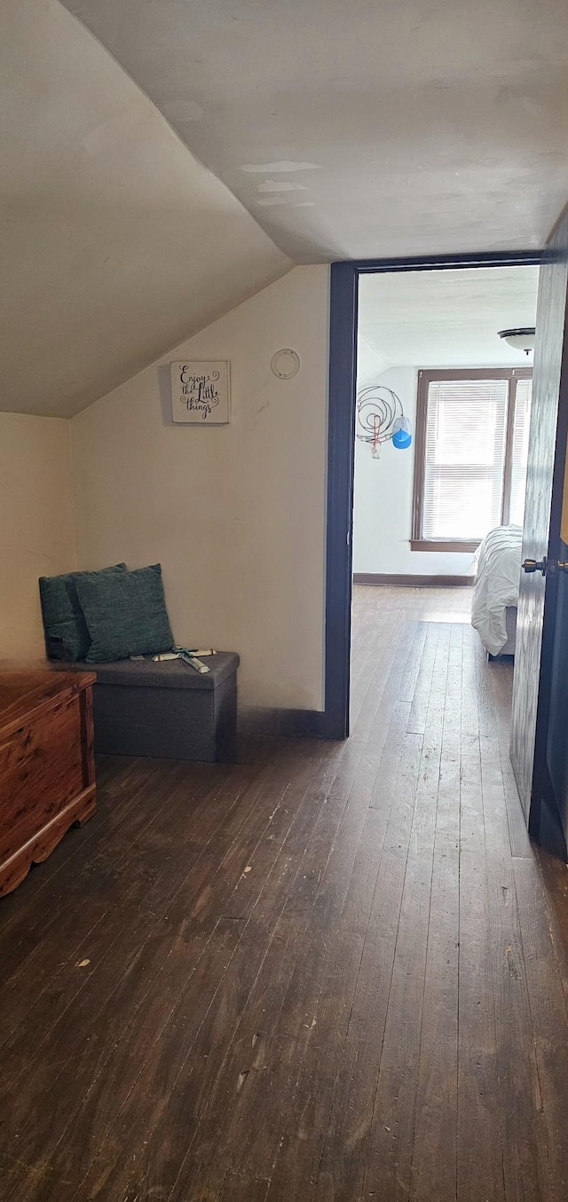 hallway with hardwood / wood-style flooring, baseboards, and lofted ceiling