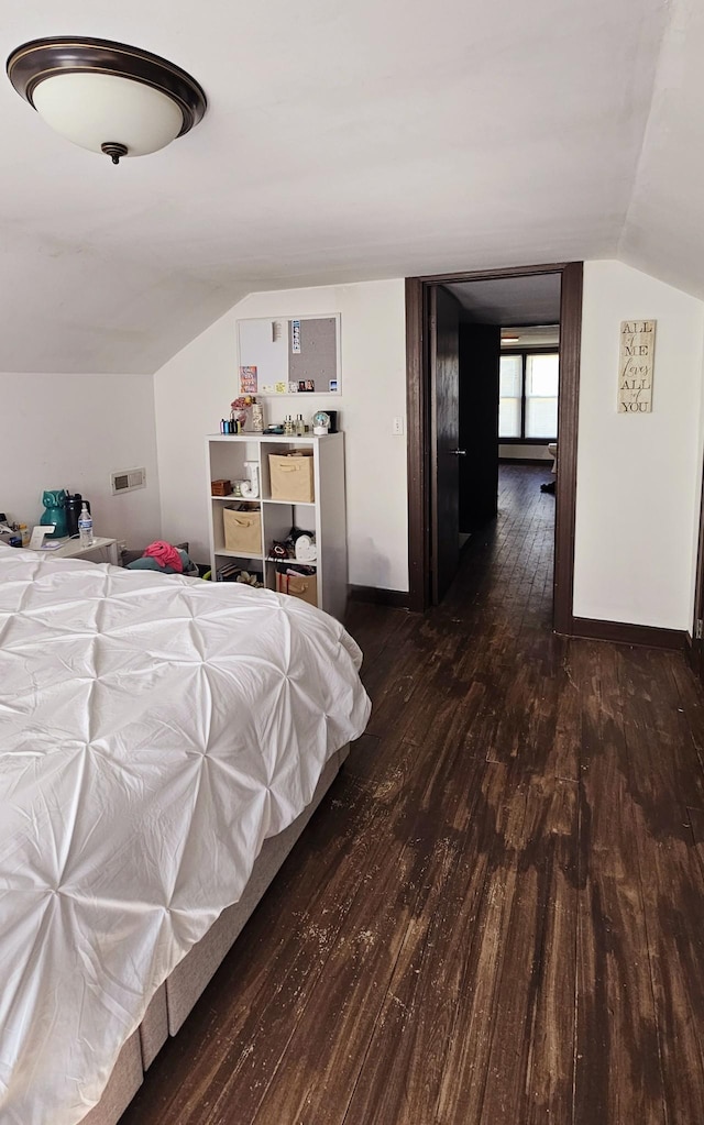 bedroom featuring baseboards, wood finished floors, and vaulted ceiling