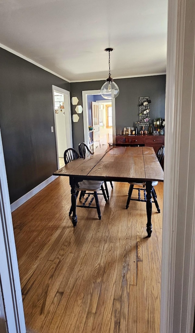 dining area with wood finished floors, baseboards, and ornamental molding