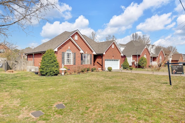 view of front of house with brick siding, an attached garage, a front lawn, fence, and driveway