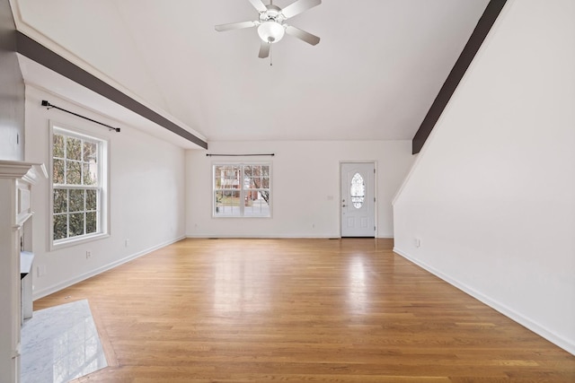 unfurnished living room featuring a wealth of natural light, light wood-style flooring, a fireplace, and vaulted ceiling