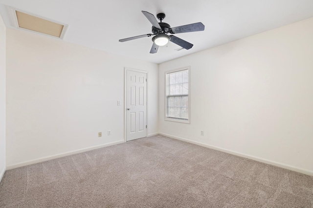 unfurnished room featuring light colored carpet, attic access, baseboards, and ceiling fan