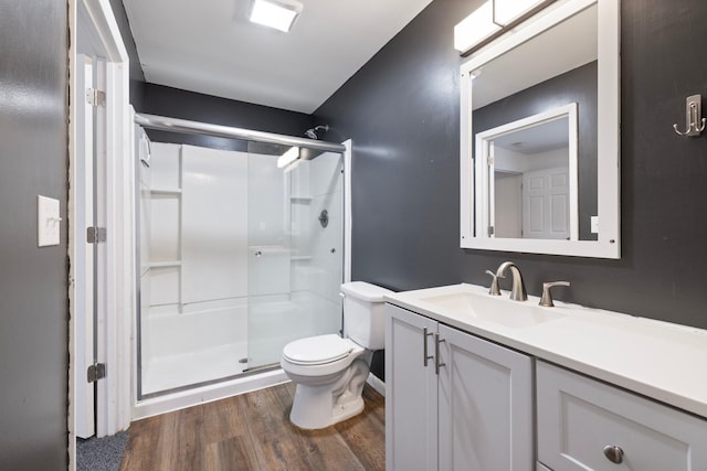 full bath featuring toilet, a stall shower, vanity, and wood finished floors