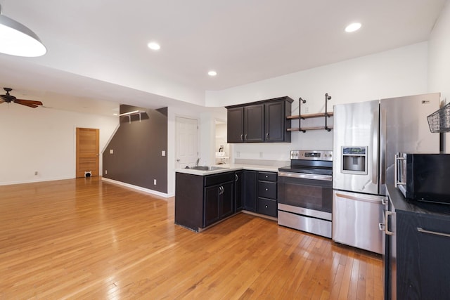 kitchen featuring a ceiling fan, light wood-style flooring, a sink, stainless steel appliances, and open floor plan