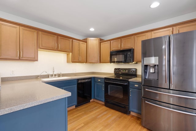 kitchen featuring light wood-type flooring, light countertops, recessed lighting, black appliances, and a sink