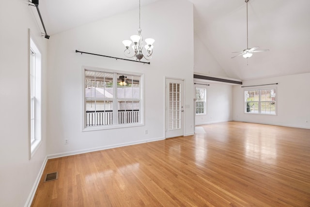 unfurnished living room with visible vents, light wood-style flooring, high vaulted ceiling, and ceiling fan with notable chandelier