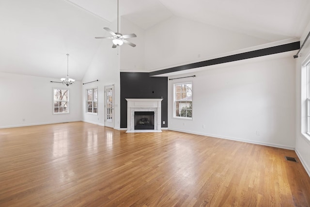 unfurnished living room with light wood finished floors, a healthy amount of sunlight, visible vents, and a high end fireplace