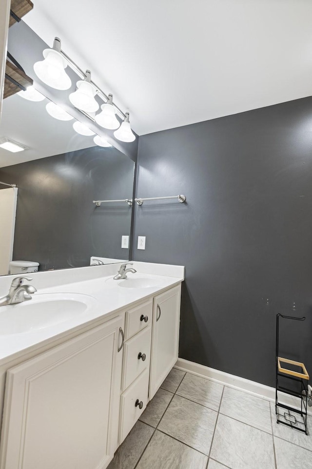 bathroom with double vanity, baseboards, tile patterned floors, and a sink