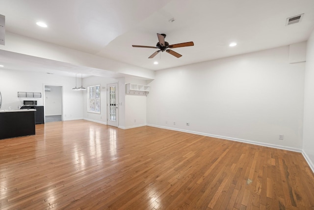 unfurnished living room featuring visible vents, baseboards, a ceiling fan, and light wood finished floors