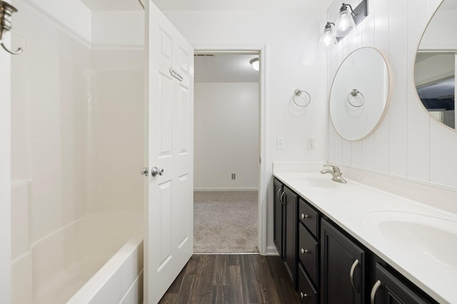 bathroom featuring double vanity, shower / tub combination, wood finished floors, and a sink