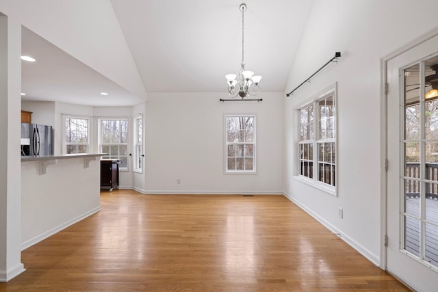 unfurnished dining area featuring vaulted ceiling, a notable chandelier, plenty of natural light, and light wood-type flooring