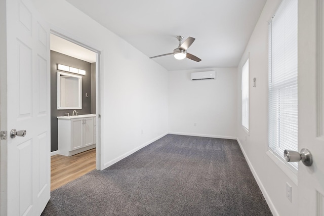 carpeted empty room featuring baseboards, ceiling fan, and a wall unit AC