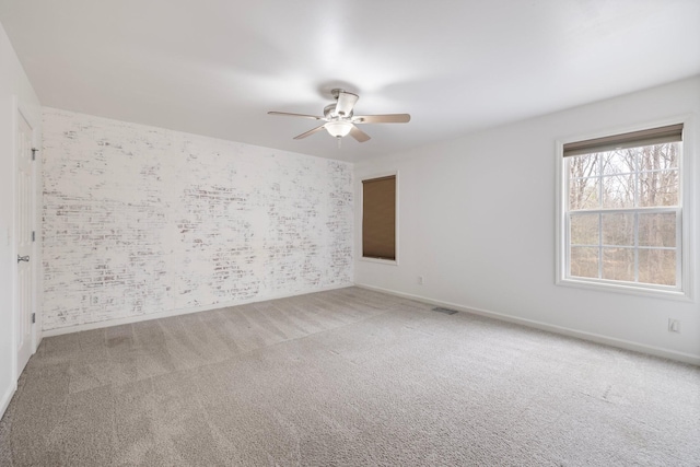 carpeted spare room with visible vents, ceiling fan, wallpapered walls, and baseboards