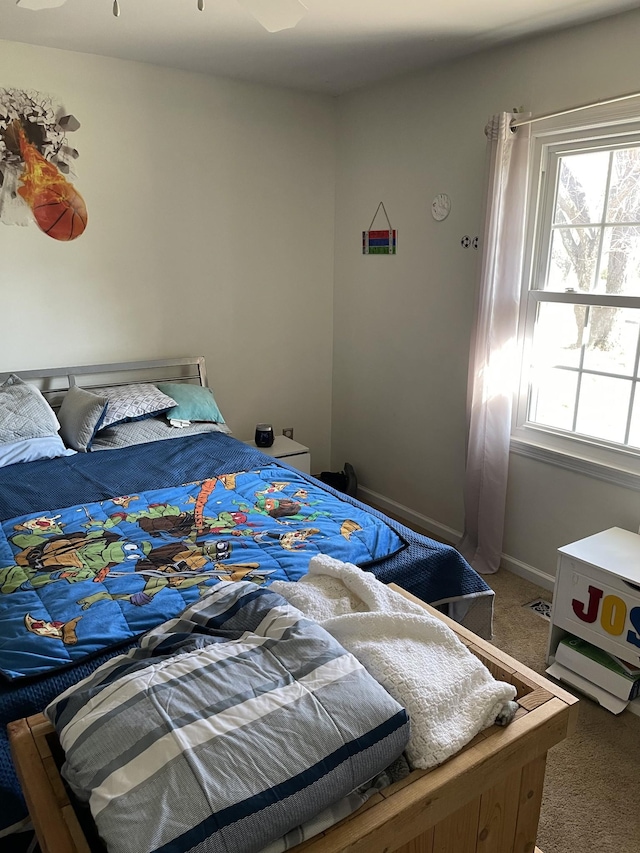 carpeted bedroom featuring multiple windows and baseboards